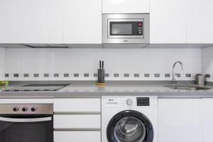 Biała kuchnia z pralką i kuchenką mikrofalową w obiekcie DV Properties Residencial Apartment #P4F2 w Maladze