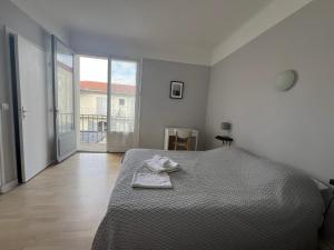 a white bedroom with a bed and a large window at Hôtel La Pergola - centre ville in Capbreton