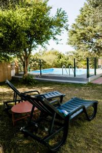 Una silla y una mesa en el césped con una piscina. en Quinta Alto da Capela, en Setúbal