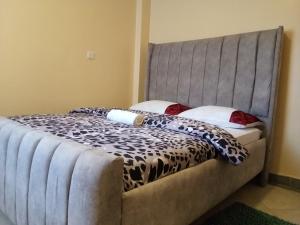 Un dormitorio con una cama con cabecero gris. en Lee's Sweet Home, en Thika