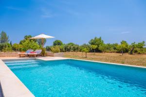 a swimming pool with a table and an umbrella at Ses Planes -Ca Na Faustina- in Selva