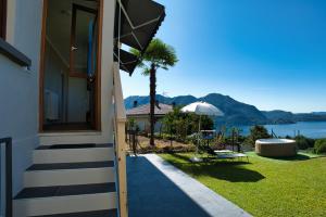 a house with a patio with a view of the water at Casa 24 - Trilocale con Vista Lago, Giardino e Idromassaggio Gonfiabile in Arizzano