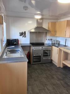 a kitchen with a stove and a sink in it at Perfect getaway Cabin Haf with Hot Tub in Llanrhaeadr-ym-Mochnant