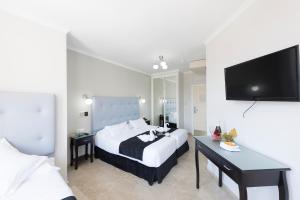 a hotel room with a bed and a flat screen tv at Hotel Toboso Chaparil in Nerja