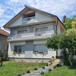 a house with balconies and flowers in a yard at Ramonda Smještaj in Tuzla