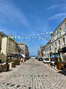 a cobblestone street in a town with a string of flags at Panorama XL Mer et Falaises à Ault in Ault