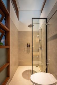a bathroom with a glass shower with a toilet at Casa Sachi & Casa Halona in Sanur +23 photos