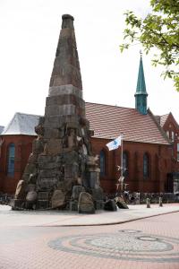 a monument in front of a building with a church at Inselhotel Cornelius in Norderney