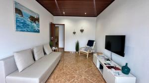 Una sala de estar con un sofá blanco y un televisor de pantalla plana. en Chloe's Beach House, en A dos Cunhados
