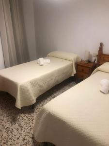 two beds in a hotel room with towels on them at 5 Apartamentos Cómodos en el Corazón de Baza in Baza