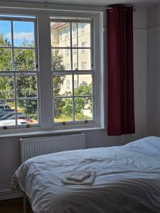 a bedroom with a bed and two windows at Flat in Hammersmith - Close to tube station in London
