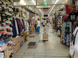 un grupo de personas caminando por el pasillo de una tienda en 東京の中心地 Okachimachi Staypia, en Tokio