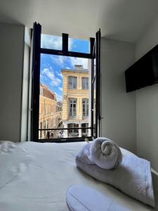 a bed with a towel on top of it with a window at LILLEHOSTS 1, Vieux Lille, Newly renovated, Modern & Stylish apartment, perfectly located in Lille