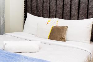 a bed with white sheets and pillows on it at Naanyu Homestays in Nanyuki