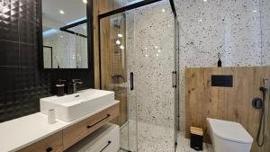 a bathroom with a sink and a glass shower at Apartament Coco Xanel- Parking- WiFi - Klimatyzacja- FV in Łódź +10 photos