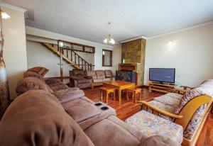 a living room with a large couch and a television at Solio Gardens Nanyuki in Nanyuki