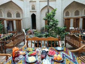 a table with plates of food on top at Aist Hotel Bukhara in Bukhara