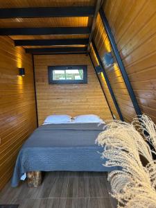 a bed in a wooden room with a window at Orange Cottage in Agara