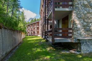 a building with a green yard next to a fence at iFlat Appartamento Pineta in Breuil-Cervinia