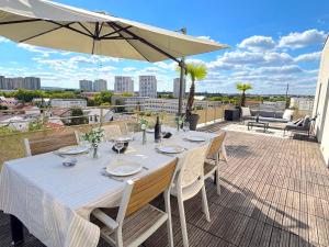 een tafel met stoelen en een parasol op een terras bij Le Penthouse Ampère in Nanterre