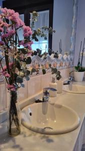 Un baño con un lavabo y flores rosas en un jarrón. en Casa Villamor de Orbigo, 