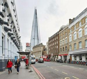two people walking down a city street with a tall building at Luxury Loft Apartment in London Bridge in London
