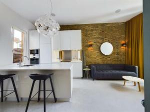 a kitchen and living room with white cabinets and a blue couch at Luxury Loft Apartment in London Bridge in London