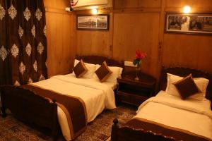 two beds in a room with wooden walls at Peace Of Mind Group of Houseboats in Srinagar