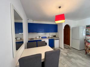 Una cocina con gabinetes azules y una mesa con sillas. en Luna Dorada Vera Playa- bajo, en Los Amarguillos