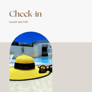 un chapeau jaune et des lunettes assis à côté d'une piscine dans l'établissement Cabo Frio Espaço Girassol, à Cabo Frio