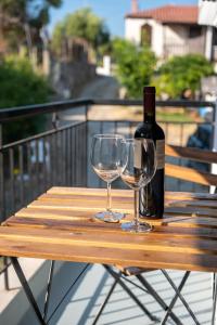 a bottle of wine and two glasses on a wooden table at Stella's Apartments in Nea Skioni
