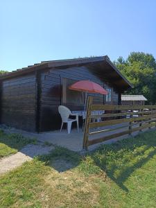Una pequeña cabaña con una mesa y una sombrilla roja. en Chalet 35m2 Domaine du vieux chêne, en Bergerac