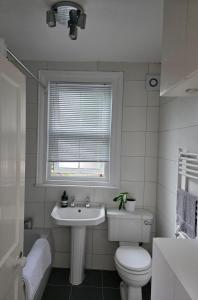 a bathroom with a toilet and a sink and a window at Walk to Wembley Stadium and Arena 2 Bedroom Sleeps 4 in London
