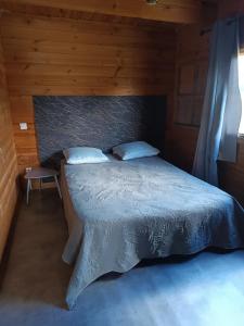 Un dormitorio con una cama en una habitación de madera. en Chalet 35m2 Domaine du vieux chêne, en Bergerac 8 fotos más