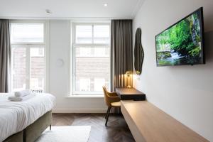 a bedroom with a desk and a tv on a wall at Anegang Boutique Hotel in Haarlem