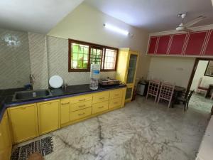 a kitchen with yellow cabinets and a counter top at Thuyil Home Stay in Tirunelveli