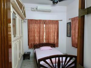 a small bedroom with a bed and a window at Thuyil Home Stay in Tirunelveli