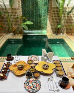 a table with cookies and pastries on it next to a pool at Riad Dar Timrad in Fez