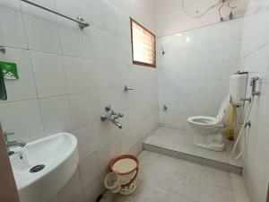 a white bathroom with a toilet and a sink at Thuyil Home Stay in Tirunelveli