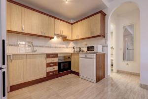 a kitchen with wooden cabinets and a white appliance at Anna del Mar Coastal Boho in San Luis de Sabinillas
