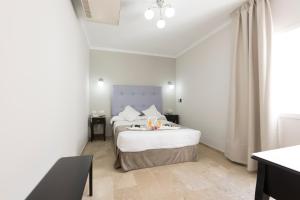 a white bedroom with two beds and a window at Hotel Toboso Chaparil in Nerja