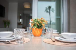 a table with plates and glasses and a vase with flowers at Mirador del Mar in Torrevieja