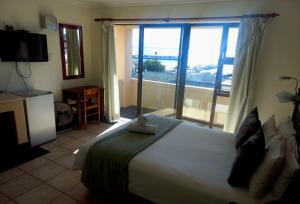 a bedroom with a large bed and a large window at Green Door Guesthouse in Mossel Bay