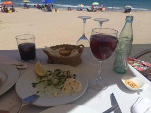 einen Tisch mit einem Teller Essen und Weingläsern am Strand in der Unterkunft Broadway es Mar in El Perelló + 35 Fotos