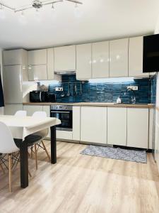 a kitchen with white cabinets and a table with chairs at Bálics Vendégház in Pécs