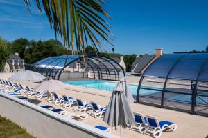 a pool with chairs and umbrellas next to a building at Résidence Odalys Horizon Morgat in Crozon