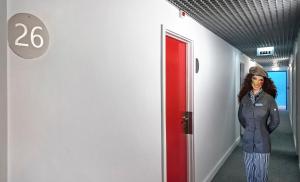 a woman standing in a hallway next to a red door at Hotel Joao XXI in Braga