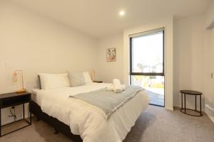 een slaapkamer met een groot bed en een groot raam bij Luxury CBD 2Bed2Bath With Parking Near Parks in Christchurch