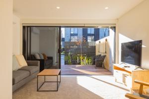 een woonkamer met een bank en een tv bij Luxury CBD 2Bed2Bath With Parking Near Parks in Christchurch