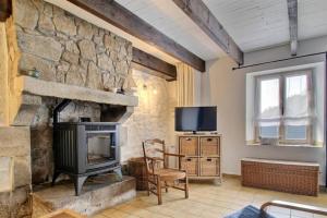 a living room with a stone fireplace and a television at Gîtes du Cosquer in Malguénac